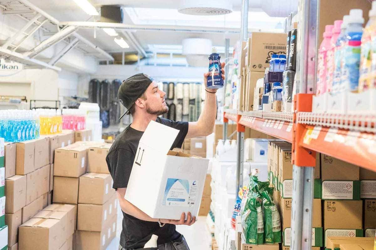 Försäljningsvillkor 1 Man plockar städprodukter och hygienprodukter från hylla